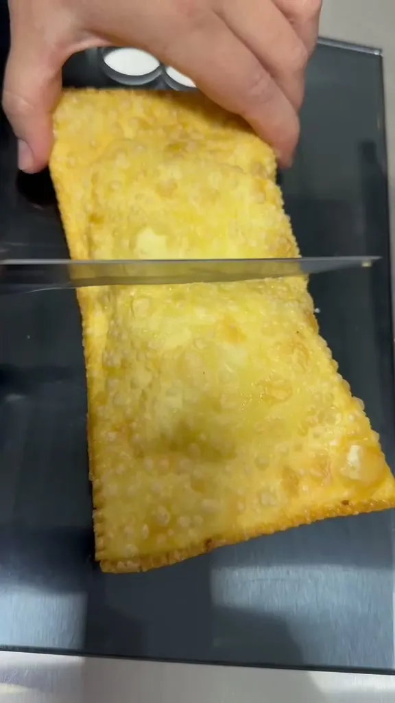 Pastel sendo cortado ao meio, mostrando a massa fininha
